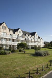 a large white apartment building with a grass field at Residence Port du Crouesty - maeva Home in Arzon