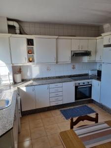 a white kitchen with white cabinets and a table at Concepción Arenal 175 in Marín