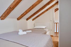 two beds in a white room with wooden ceilings at Villa Dora in Omiš centar now with Jacuzzi in Omiš