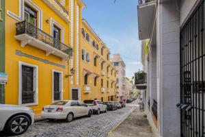 una strada con edifici gialli e auto parcheggiate sulla strada di Old San Juan Gateway Gem a San Juan