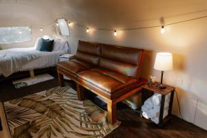 a living room with a leather couch and a bed at The Juniper Ranch and Retreat in Canyon Lake