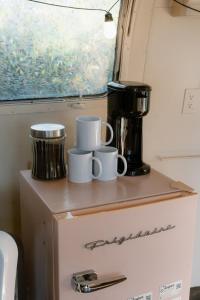 Un estante con tazas encima de un refrigerador. en The Juniper Ranch and Retreat, en Canyon Lake