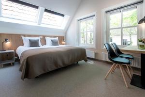 sypialnia z łóżkiem i biurkiem oraz 2 oknami w obiekcie Leut logies & Boutiquehotel het Eiland w mieście Oost-Vlieland
