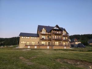 a large house on a hill with a grass field at Crown Apartmani Vlašić in Vlasic