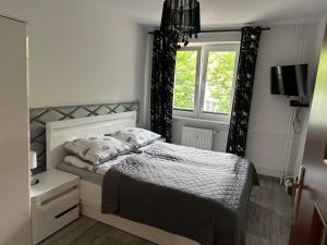 a small bedroom with a bed and a window at Apartament Słowiańska by Zilla in Ustka
