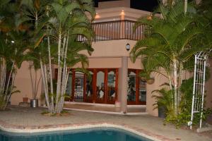a hotel with a swimming pool and palm trees at Tengo guest house in Phalaborwa
