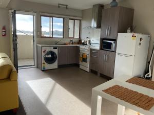 a kitchen with a refrigerator and a washer and dryer at Spacious Studio - Self Contained in Tauranga