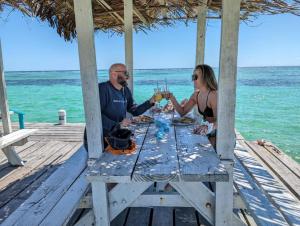 a man and woman sitting at a picnic table on the beach at Tranquility Bay Resort in San Pedro