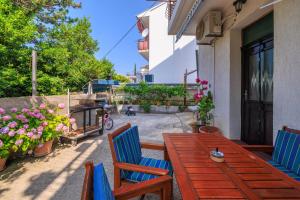 a patio with a wooden table and chairs and flowers at Apartment Vlatka Grof in Selce