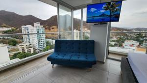 a blue chair in a room with a large window at Hermoso Apartamento con doble vista Mar y montaña tipo Loft cerca a la playa instalaciones nuevas in Gaira
