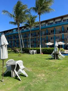 a resort with tables and chairs and palm trees and a building at Marinas Vista Mar in Tamandaré