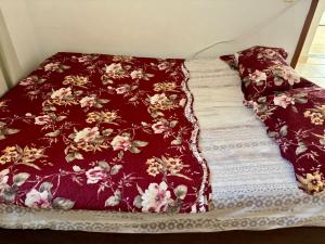 a bed with a red blanket with flowers on it at Só 1 Quarto Belle Nature in Valparaíso de Goiás +12 photos