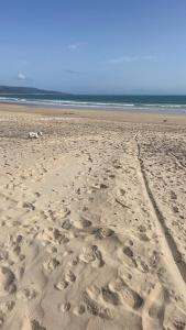 a beach with footprints in the sand and the ocean at Piso acogedor en Barbate in Barbate