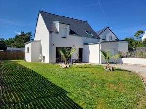 a white house with palm trees in the yard at Maison Saint Philibert 3 chambres in Saint-Philibert