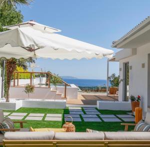 a patio with couches and an umbrella and the ocean at Divinum Mare Luxury Villa with Private Pool & Sea View just 200m from the Beach in Palaiochórion