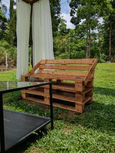 a wooden bench sitting on the grass next to a table at Tropical Crystal House in Guápiles +16 photos