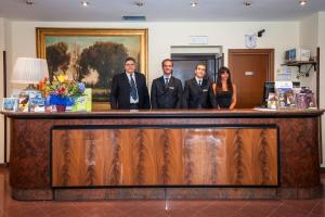 Un groupe de quatre personnes se tenant derrière un bar dans l'établissement Hotel California, à Rome