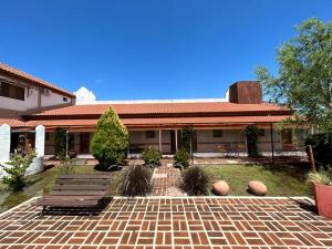 a house with two benches and a brick patio at Hosteria Manantial de Carpintería in Carpintería