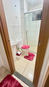 a bathroom with a toilet and a shower and pink rug at APP 2 Quartos Belle Nature in Valparaíso de Goiás