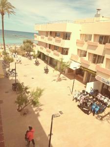 エス・プホルスにあるFormentera suite 13のビーチの隣の建物の外に座っている人々のグループ