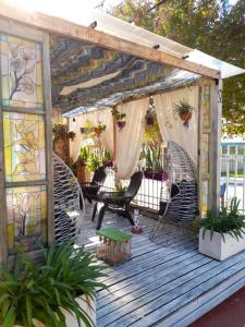 Una terraza de madera con pérgola con sillas y plantas. en Antu Kuyen Hostel, en Villa Carlos Paz