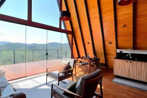 Una sala de estar con una mesa y una gran ventana. en Cabana Tempo | 2h30 SP | Vista Única | Cama King, en Santo Antônio do Pinhal