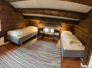a bedroom with two beds in a room with wooden walls at Sjarmerende tømmerhytte på Bjorli in Bjorli