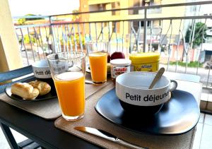 a table with two glasses of orange juice and a cup of coffee at Appartement Cayenne Hypercentre in Cayenne