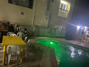 Una piscina con una mesa y gente sentada alrededor de ella. en High-Con Hotel and Suites, en Mama