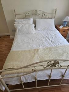 una cama grande con sábanas y almohadas blancas en Luxury Stay, en Dublín