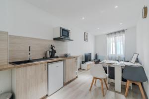 a kitchen with wooden cabinets and a table with chairs at Séjour Confort - Proche Gare & Centre - Futuroscope 1 in Châtellerault