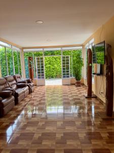 a living room with a couch and a flat screen tv at Hotel Campestre Villa Alicia in Estación El Salto