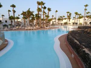 a large swimming pool with palm trees in a resort at Oasis Duna - Casa Mariposa in Corralejo