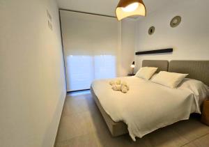 una camera da letto con un letto bianco e un orsacchiotto sopra di Casa Flamenca Apartment in Flamenca Village a Playa Flamenca Altre 42 foto