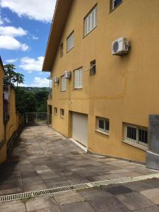 un edificio amarillo con un estacionamiento al lado en Apzito Tri com garagem, en Porto Alegre