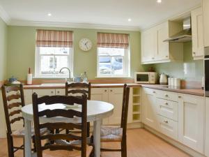 a kitchen with a table and chairs and a clock on the wall at 2 The Reading Room Cottages - Uk31801 in Barningham