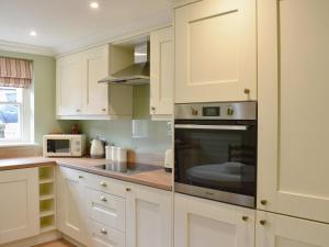 a kitchen with white cabinets and a microwave at 2 The Reading Room Cottages - Uk31801 in Barningham