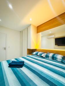 - une chambre avec un grand lit aux rayures bleues et blanches dans l'établissement Apartamento Pé na Areia com Piscina e Vista Mar ao lado do Itaparica Food Park, à Vila Velha