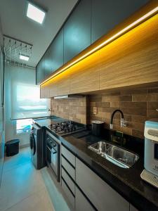 une cuisine avec un évier et une cuisinière dans l'établissement Apartamento Pé na Areia com Piscina e Vista Mar ao lado do Itaparica Food Park, à Vila Velha