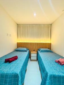 deux lits dans une chambre avec une couette bleue dans l'établissement Apartamento Pé na Areia com Piscina e Vista Mar ao lado do Itaparica Food Park, à Vila Velha 32 autres photos
