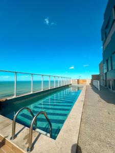 une piscine avec l'océan en arrière-plan dans l'établissement Apartamento Pé na Areia com Piscina e Vista Mar ao lado do Itaparica Food Park, à Vila Velha