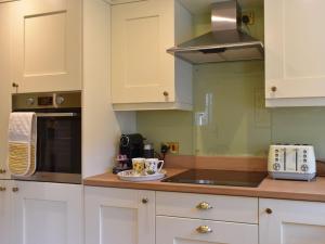 a kitchen with white cabinets and a counter top at 3 The Reading Room Cottages - Uk31802 in Barningham