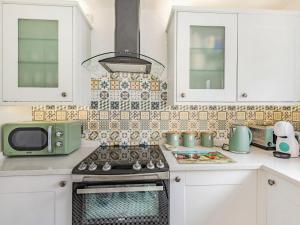 eine Küche mit weißen Schränken und einer grünen Mikrowelle in der Unterkunft Comfy Kozy Cottage in Louth + 17 Fotos