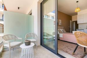 Zimmer mit einem Balkon mit einem Bett, einem Tisch und Stühlen in der Unterkunft New Coral Suite + Pool & Sauna in Nea Paphos