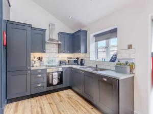 a kitchen with blue cabinets and a wooden floor at Ty Felin - Uk12744 in Acrefair