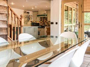 Un comedor con una mesa de cristal y sillas blancas. en Beer Farm, en Stawley
