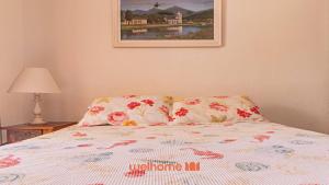 a bed with two pillows and a picture on the wall at Casa em Paraty com piscina e churrasqueira in Paraty