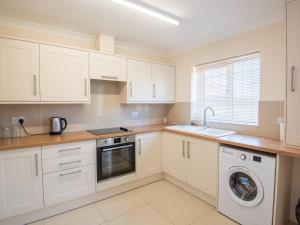 a kitchen with white cabinets and a washer and dryer at Dawson Park 8 - Uk12667 in Mablethorpe