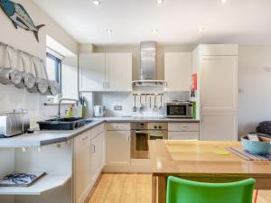 a kitchen with white cabinets and a wooden table at Crab Cottage in Wells next the Sea +8 photos
