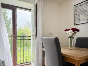 a vase of flowers on a wooden table with a window at The Coach House in Wirksworth